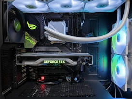 A high-end gaming or performance PC interior equipped with RGB lighting and multiple cooling fans. The graphics card prominently displayed is a GeForce RTX model, with branding visible. The setup includes neatly managed cables and a liquid cooling system.