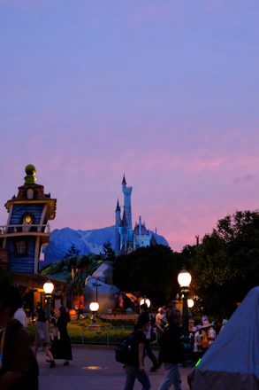 A family happily exploring a Disney castle at sunset with magical lights.