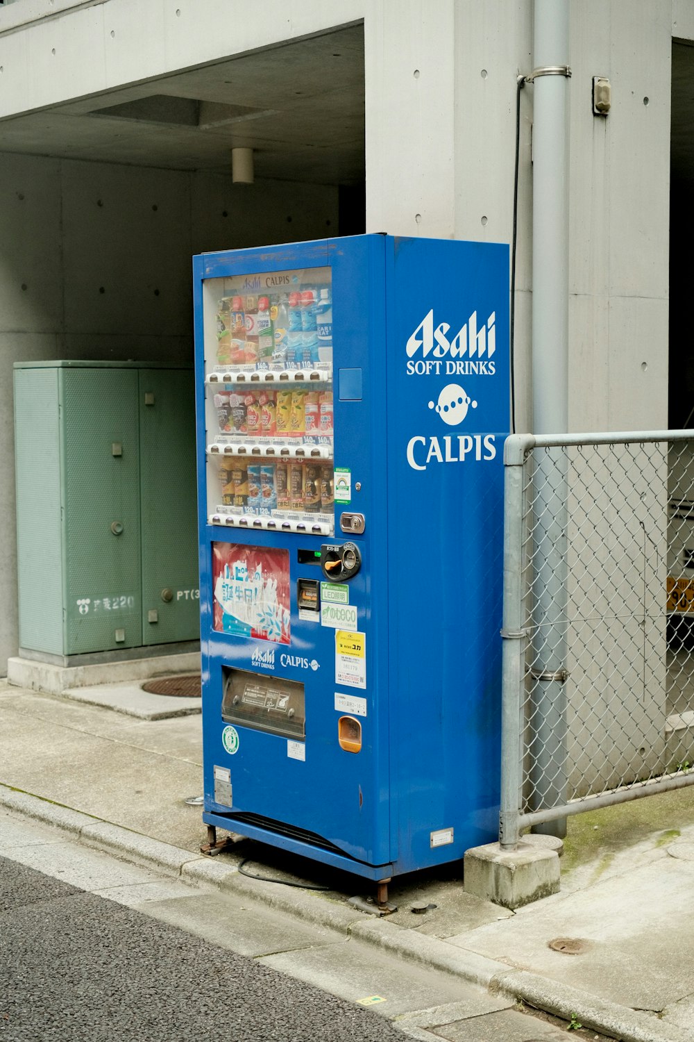 a blue vending machine sitting on the side of a road