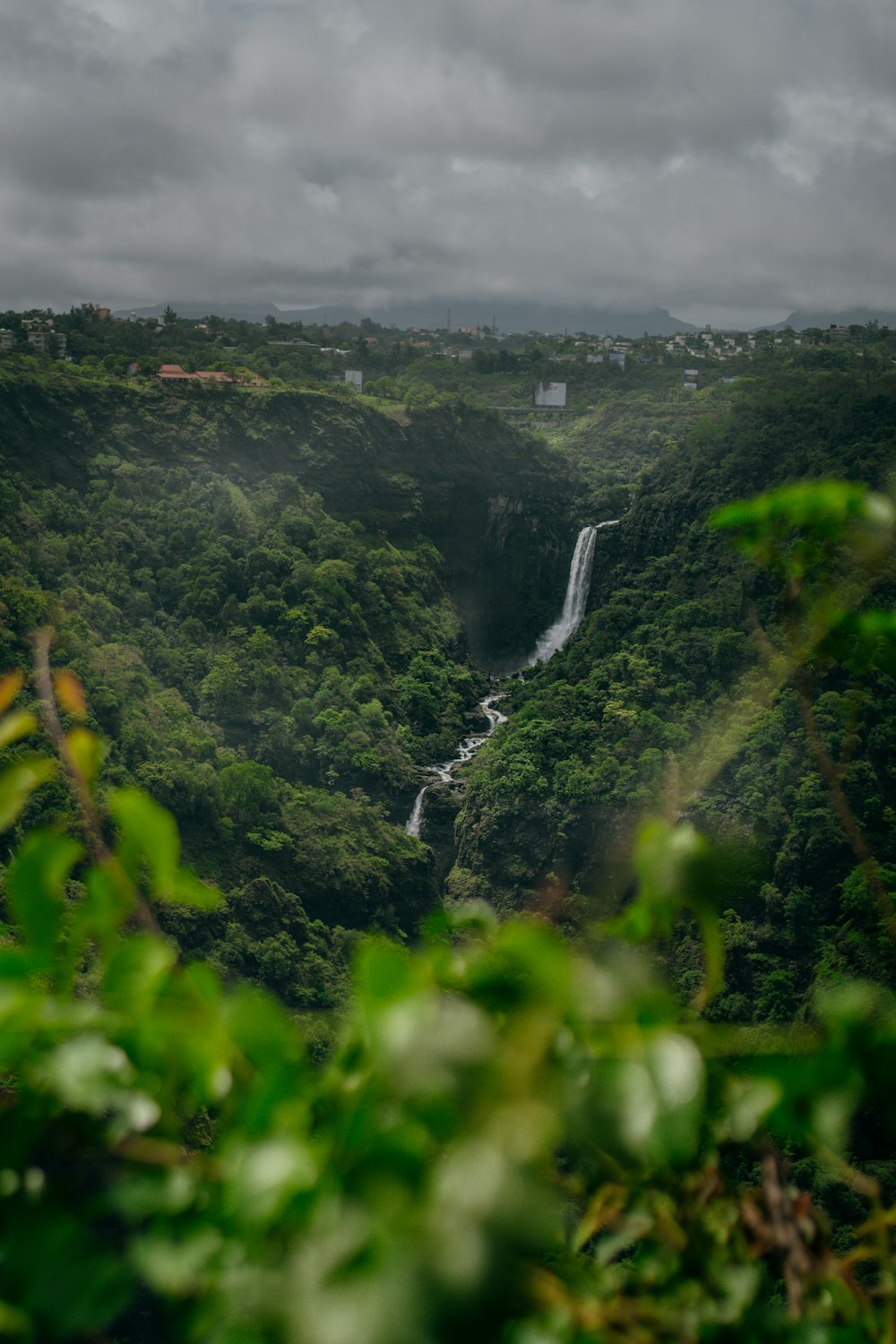 a lush green valley with a waterfall in the distance