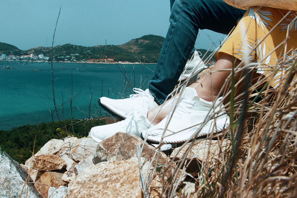 a person sitting on top of a rock near the ocean