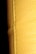 A close-up view of a textured yellow leather surface, displaying visible stitching along a seam. The background is dark, enhancing the texture and color of the leather.