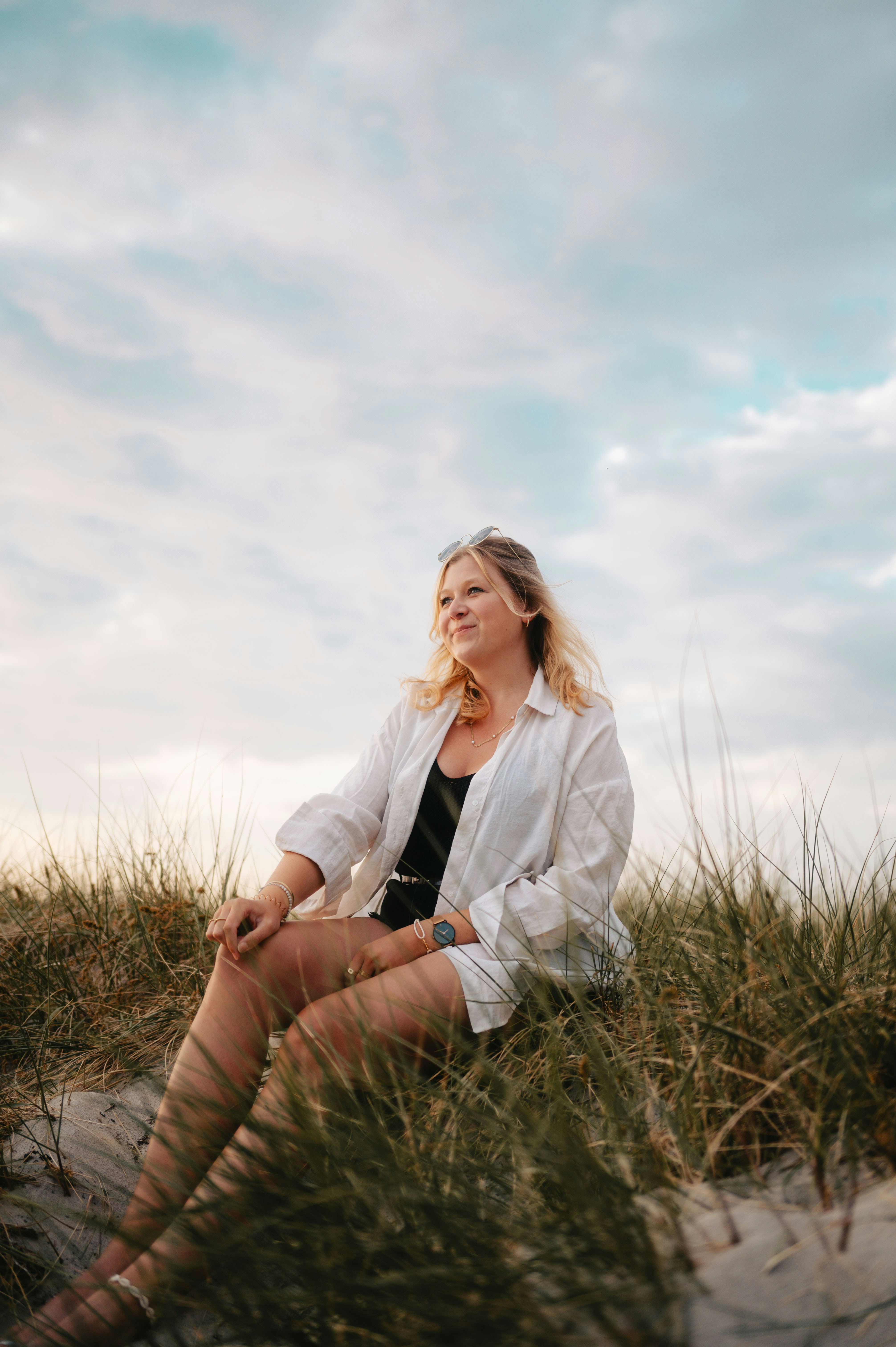 a woman sitting in the sand with her legs crossed