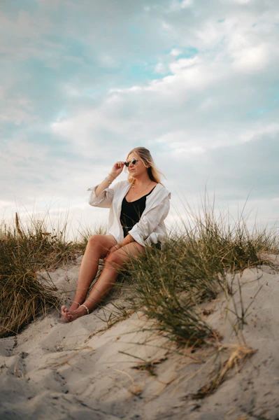 a woman sitting on top of a sandy beach