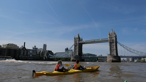 two people in a kayak in front of the tower bridge