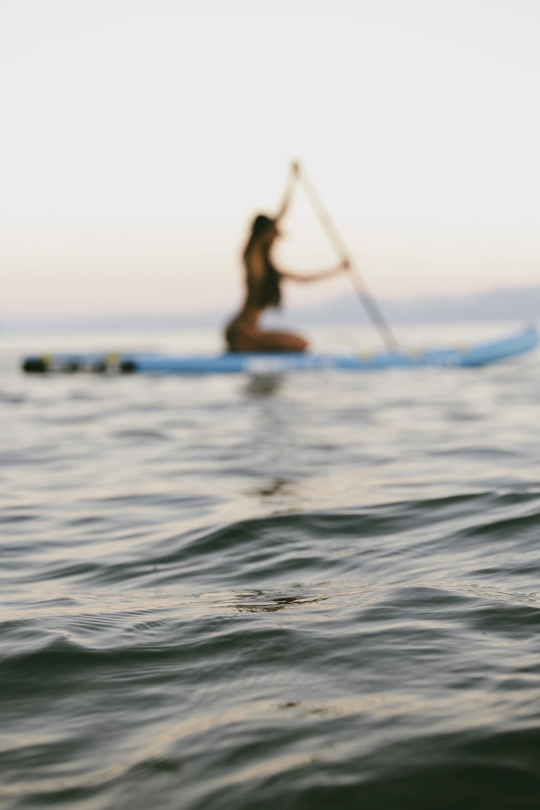 Paddle boarder moving across calm open water