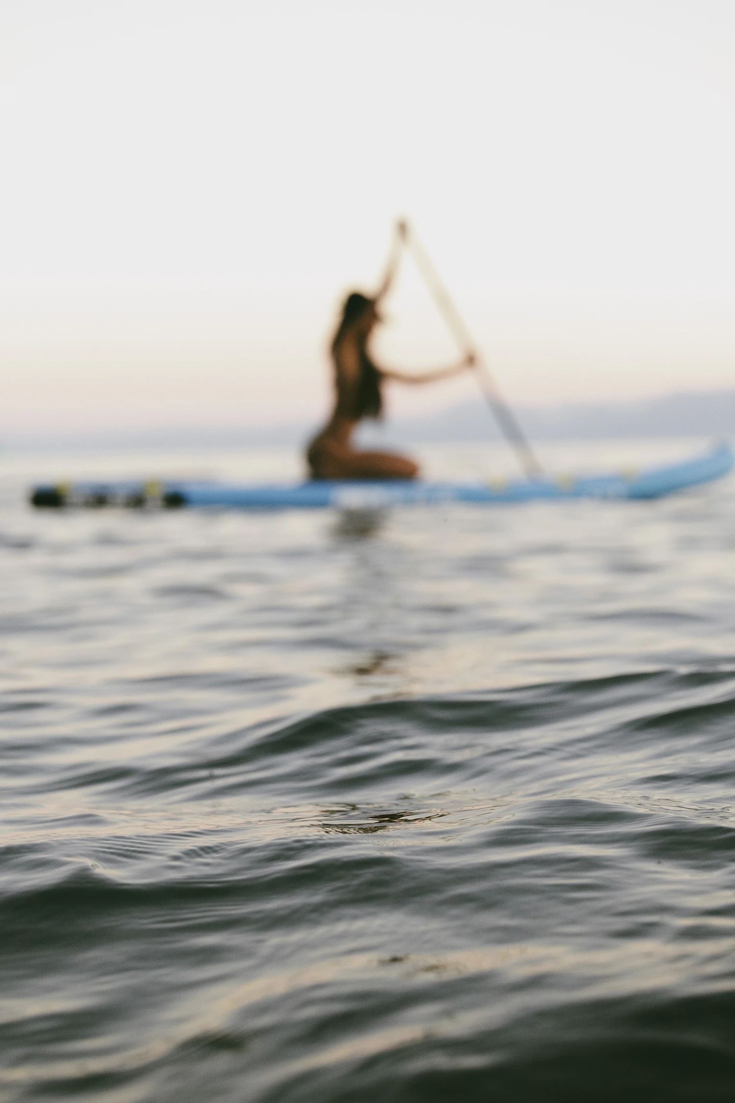 A stand-up paddleboarder moving across open water