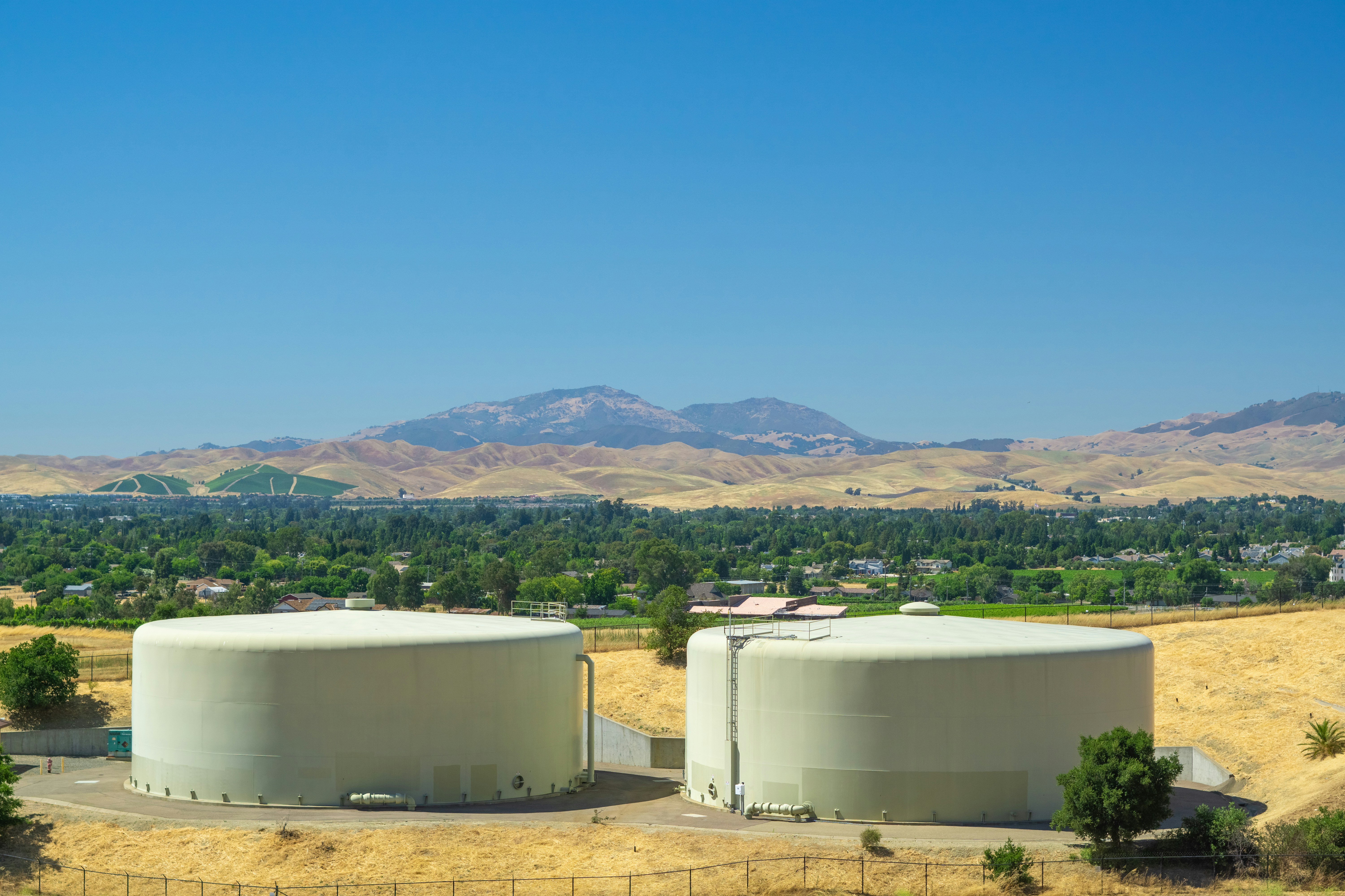 a couple of large tanks sitting on top of a dry grass field