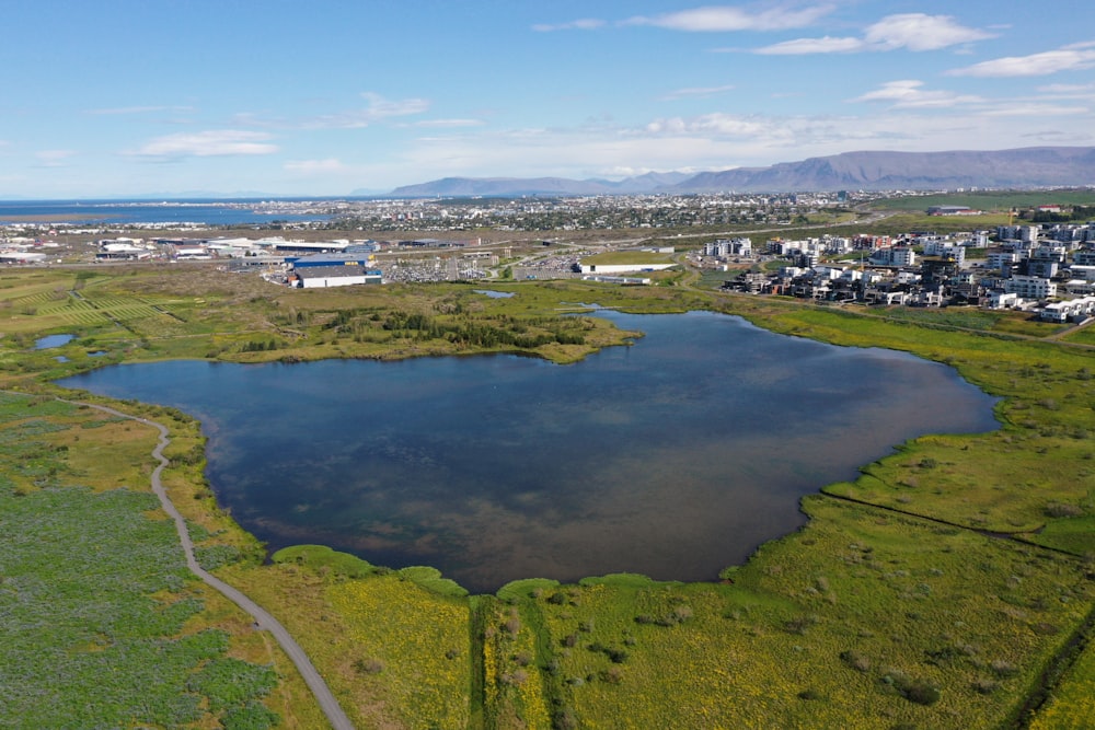 a large body of water surrounded by a lush green field