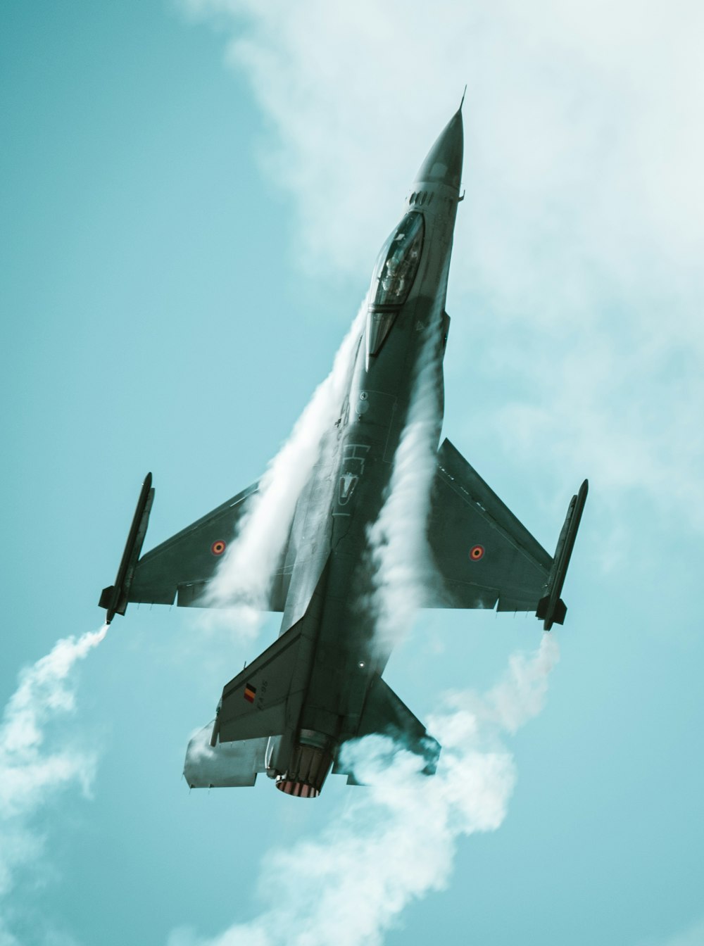 a fighter jet flying through a cloudy blue sky