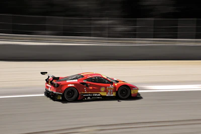 A bright red RC racing car zooming on a smooth track with checkered flags in the background