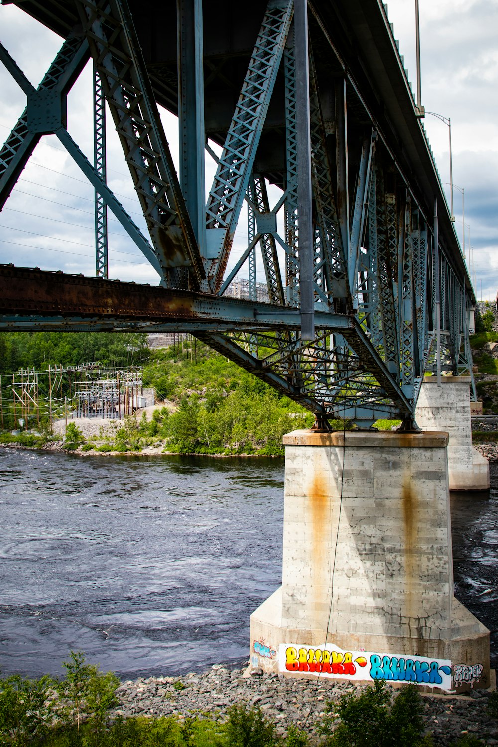 a bridge over a river with graffiti on it