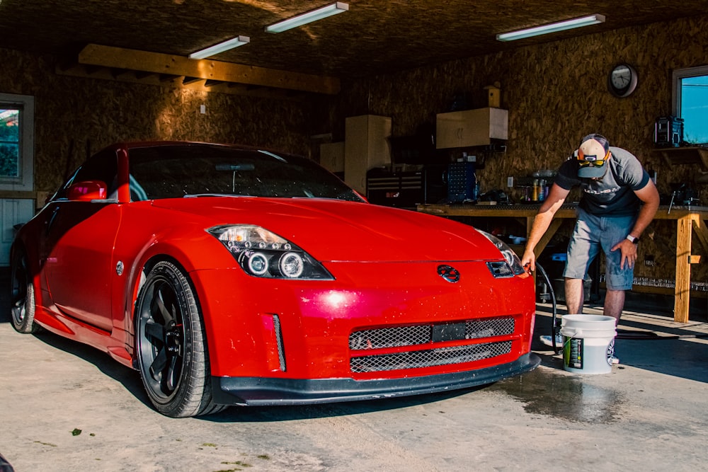 a man washing a red sports car in a garage