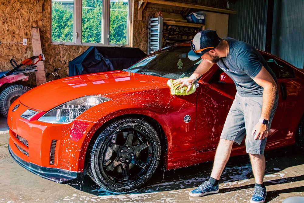 a man washing a red sports car in a garage