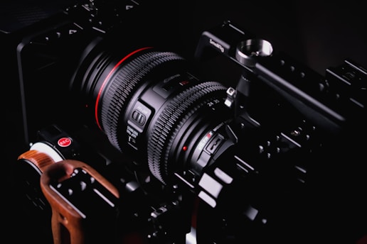 Two professional camera lenses are mounted on a camera rig. The lenses have various dials and switches for adjustments, and the rig includes handles and attachments for stability and accessory mounting.