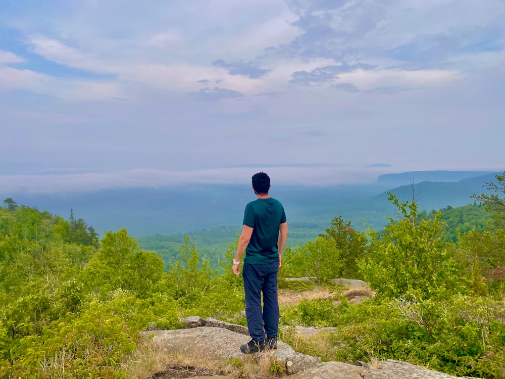 Un uomo in piedi sulla cima di una collina verde lussureggiante