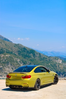 A bright yellow car from Exist Travel & Rent Car parked near a scenic mountain backdrop.