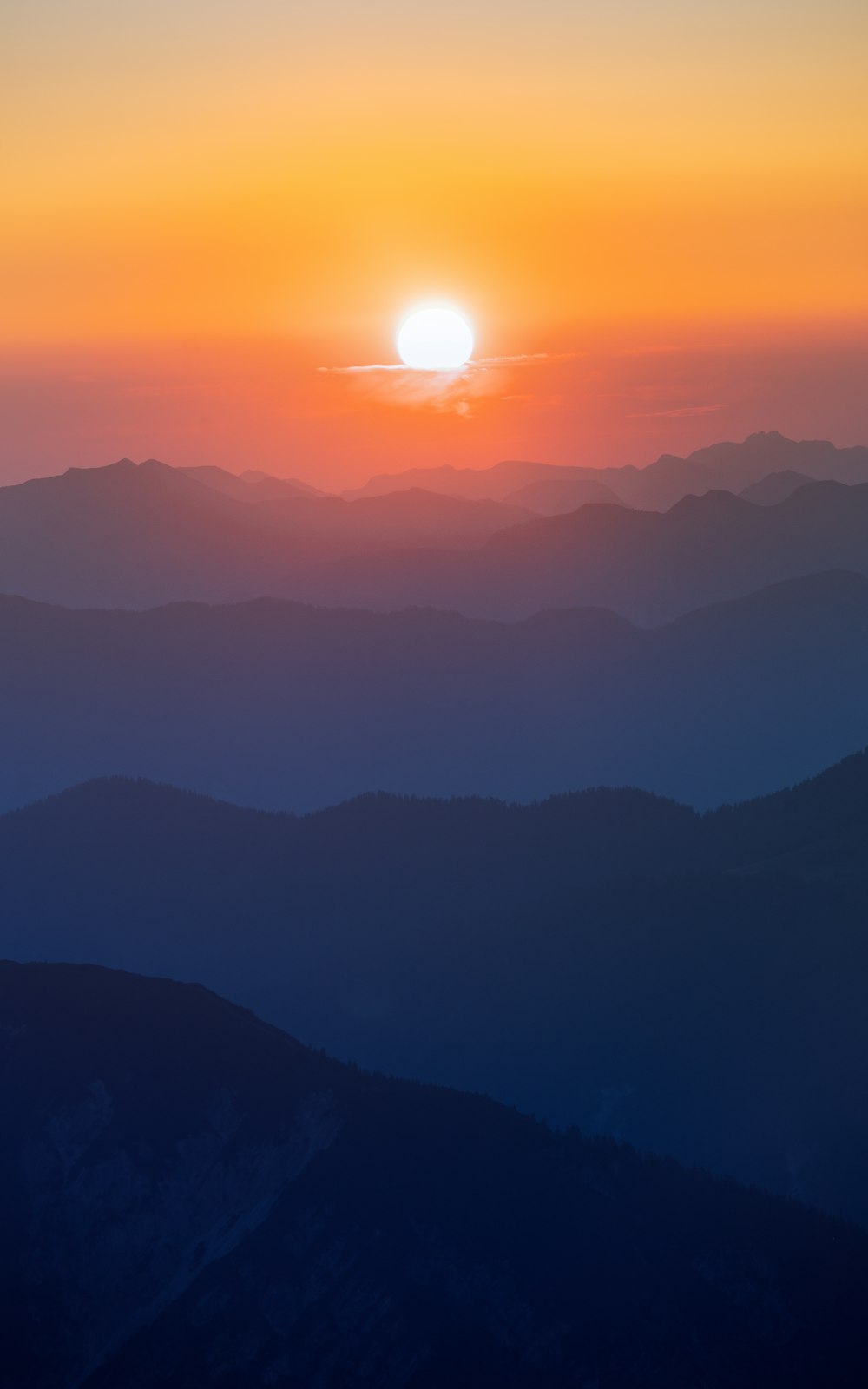 the sun is setting over a mountain range