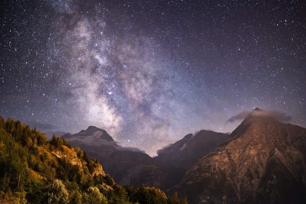 the night sky with stars above a mountain range