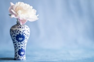 A soft taupe ceramic sculpture of a blooming peony with intricate petal details and a matte finish.