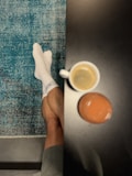 a person's feet with white socks and a cup of coffee