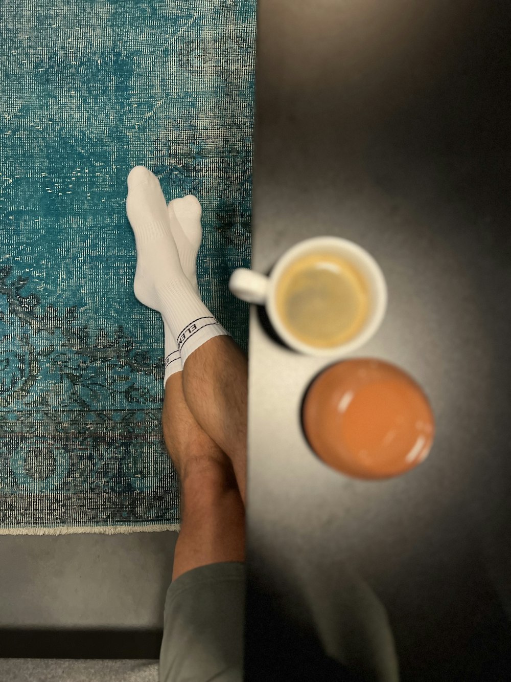 a person's feet with white socks and a cup of coffee