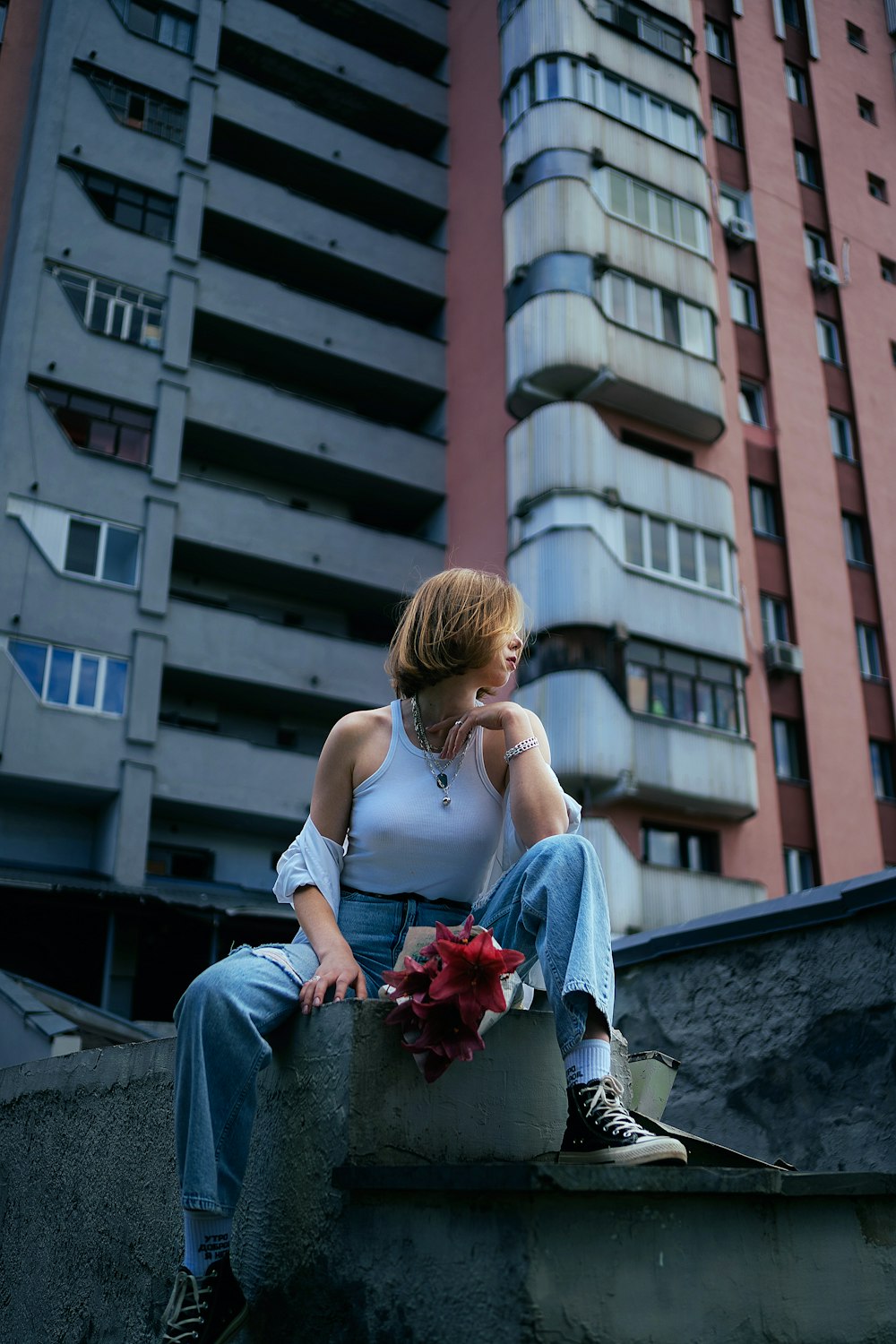 a woman sitting on a ledge in front of a tall building