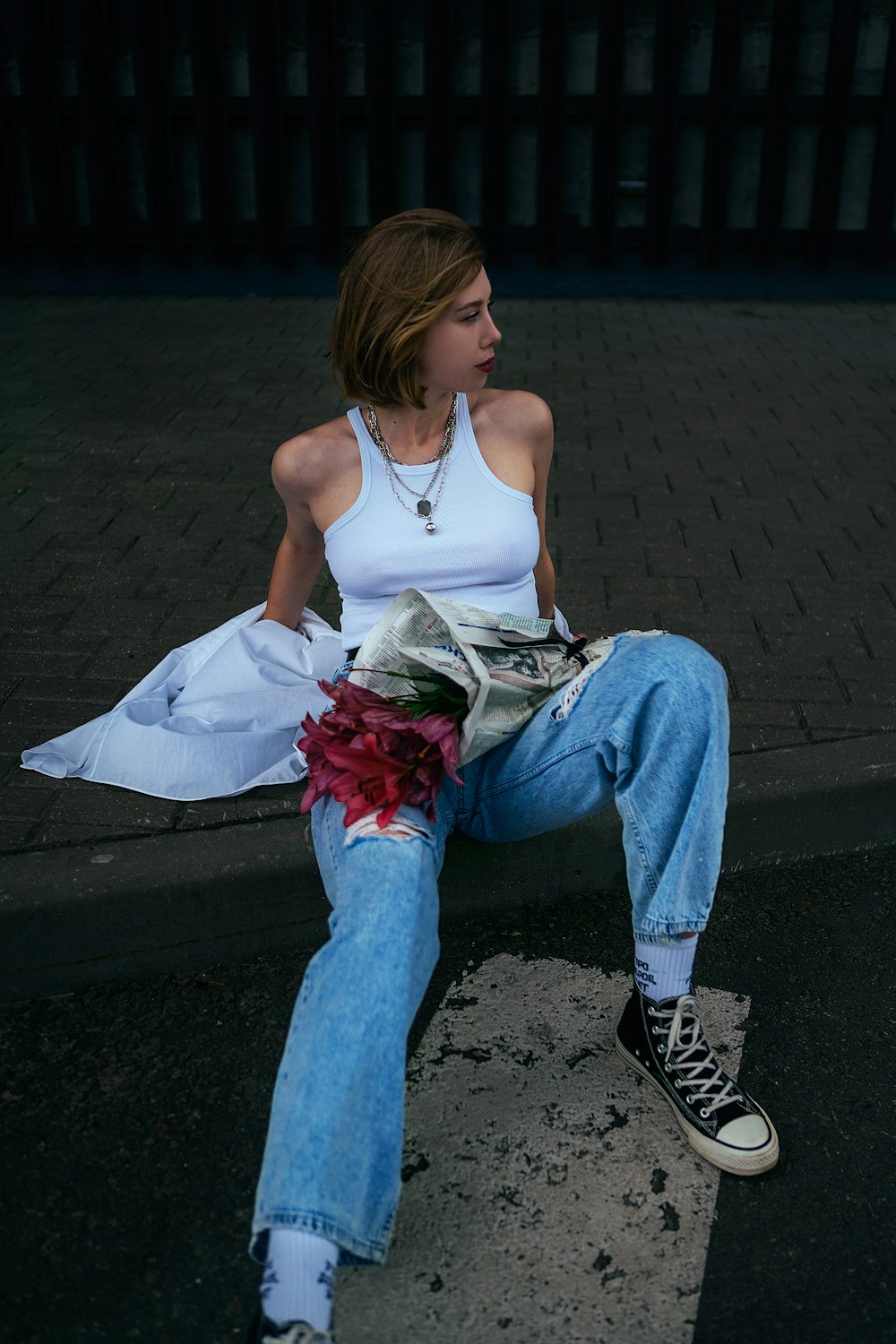 a woman sitting on the ground with a flower in her hand