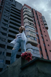 A model wearing a graphic tee and ripped jeans standing confidently on a rooftop at sunset.