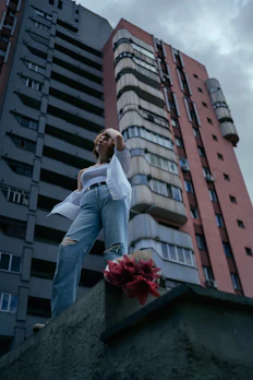A model wearing a graphic tee and ripped jeans standing confidently on a rooftop at sunset.