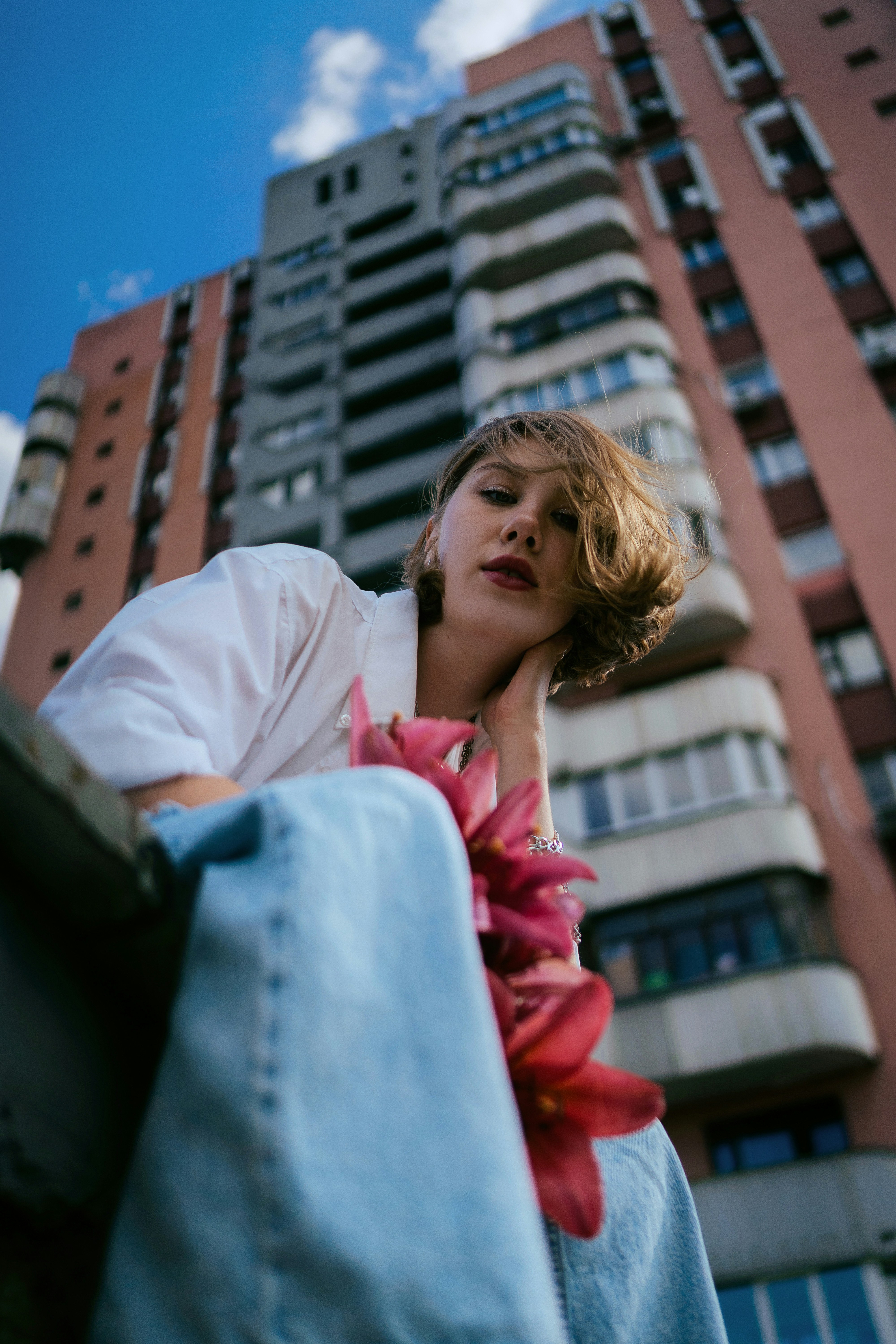 a woman leaning against a wall in front of a tall building