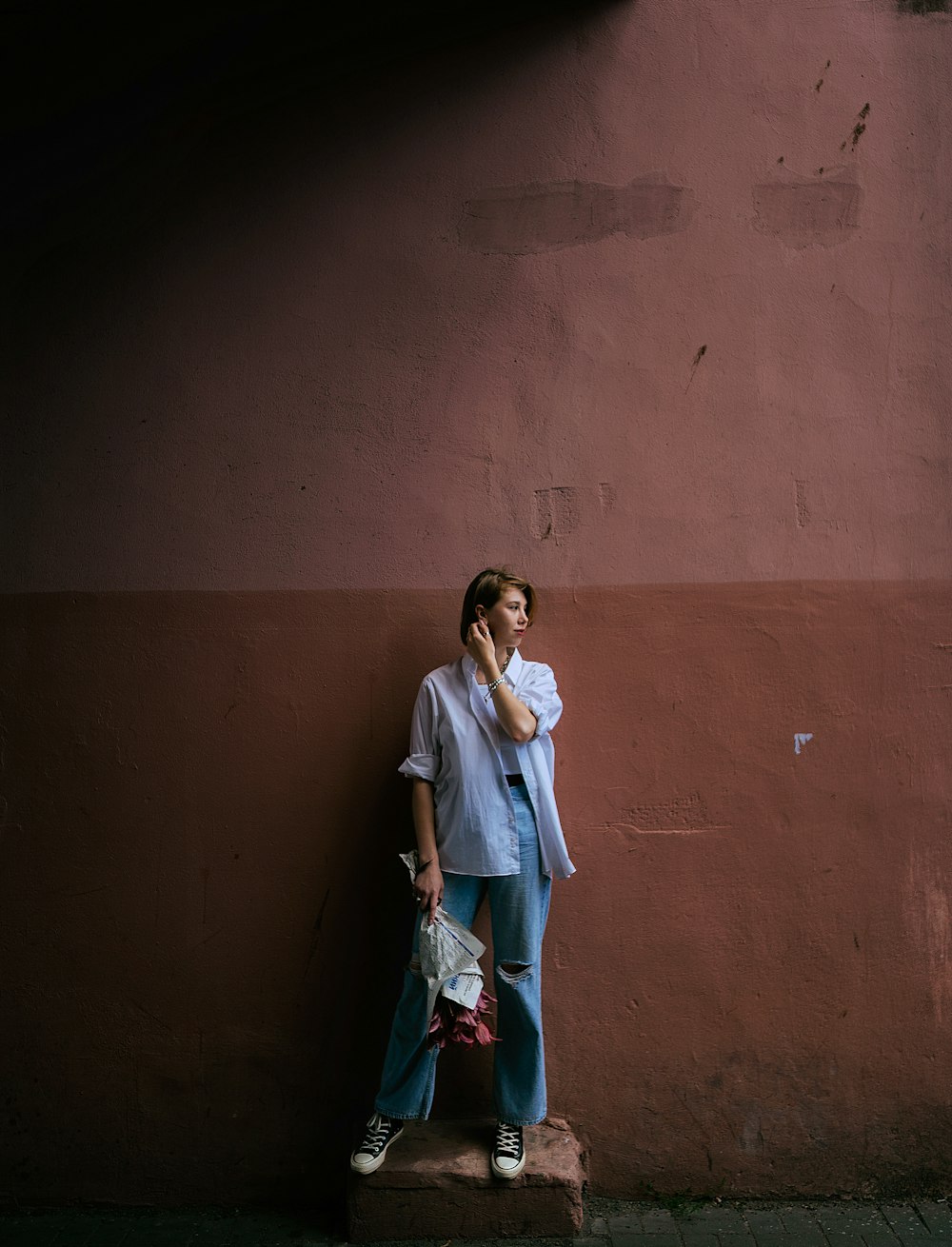 a woman leaning against a wall talking on a cell phone