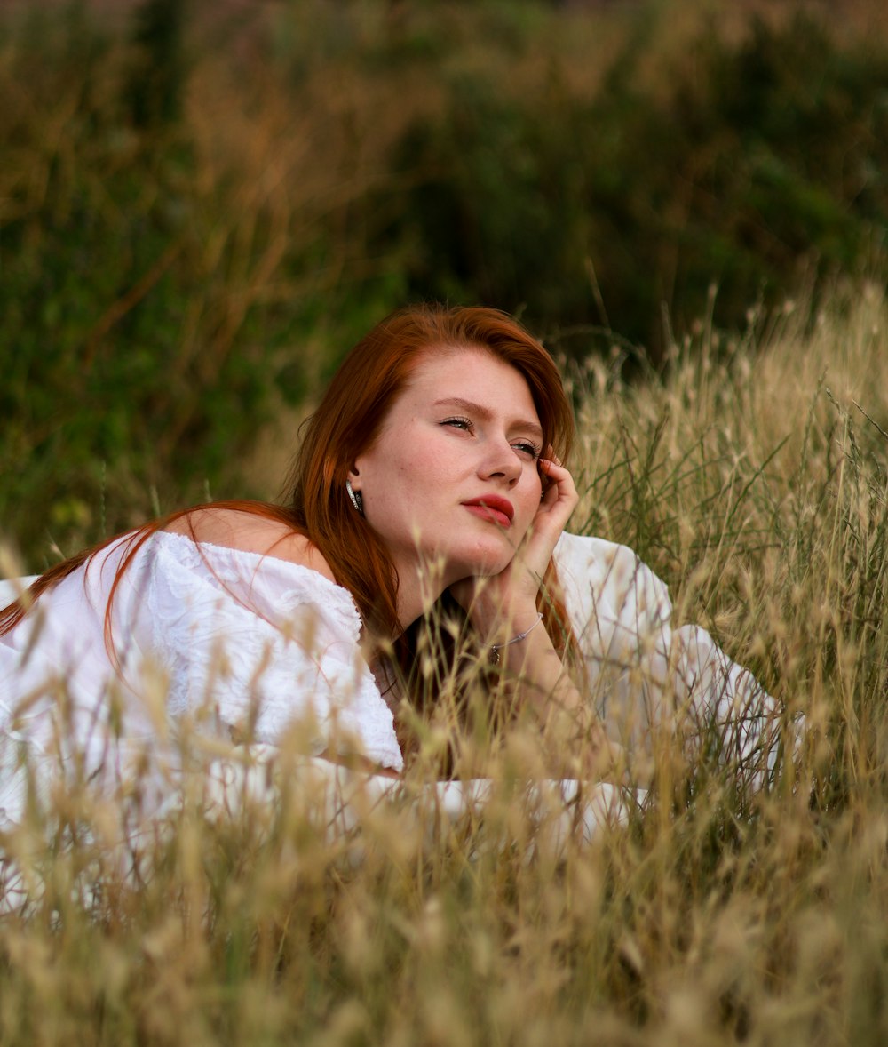 a woman laying in a field of tall grass