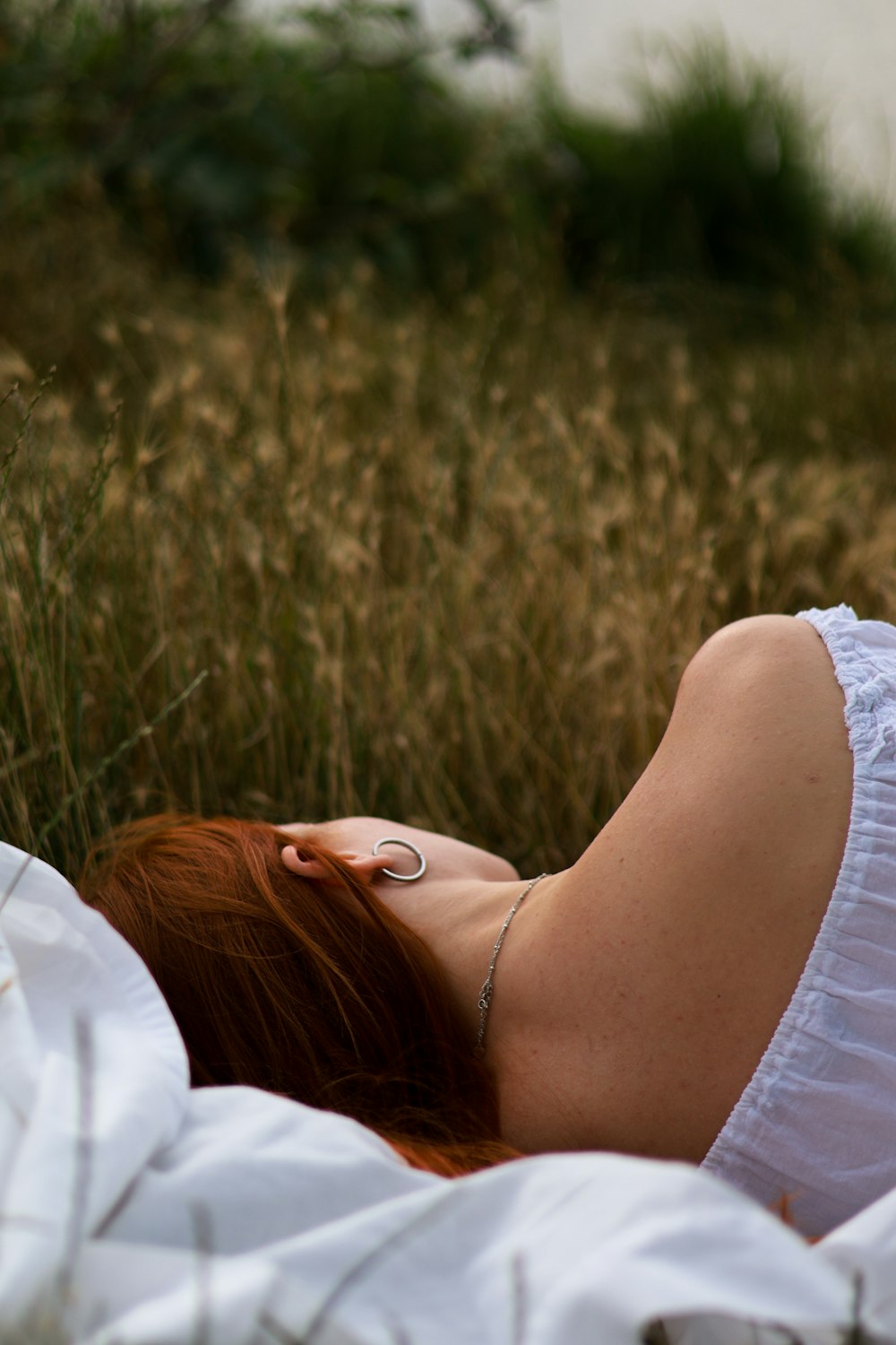 a woman laying in a field of tall grass