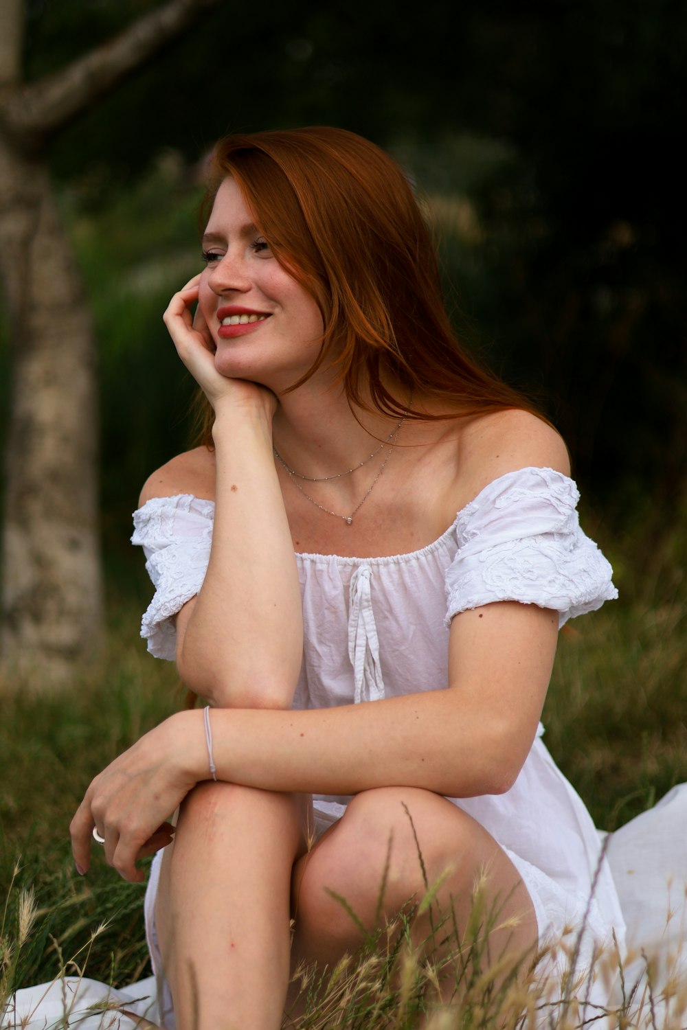 a woman in a white dress is sitting in the grass