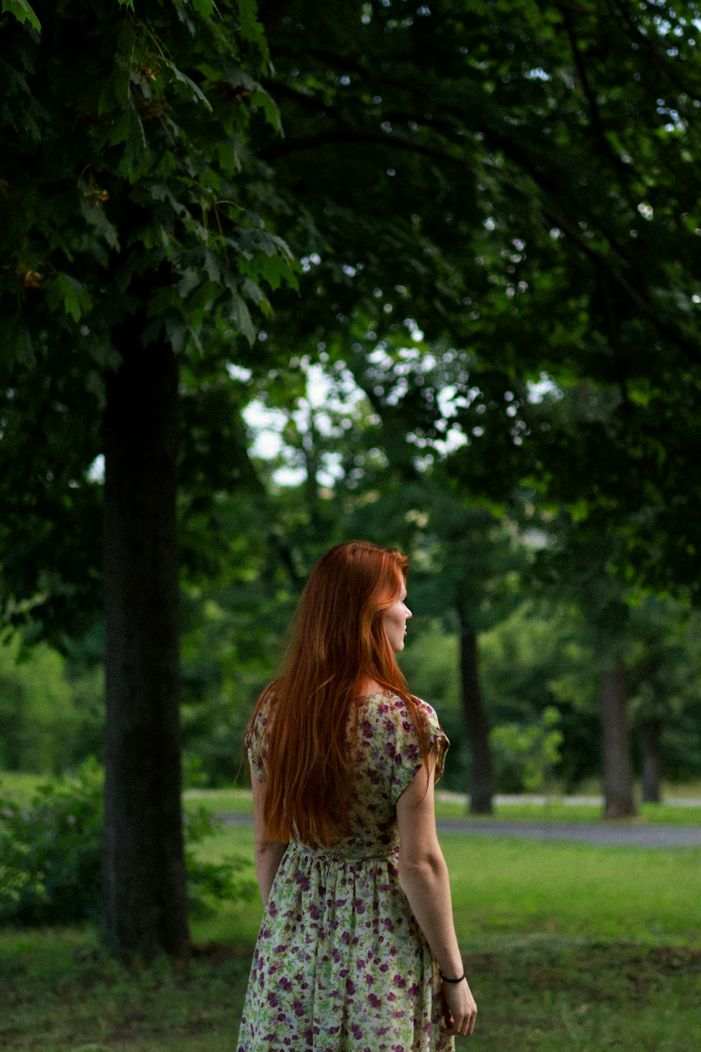 a woman with red hair standing in a park