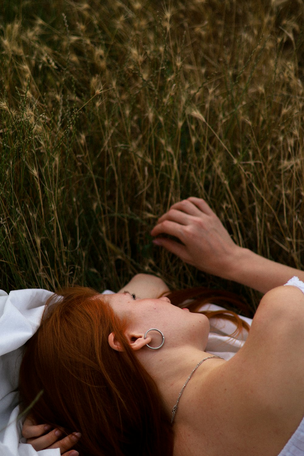 a woman laying in a field of tall grass