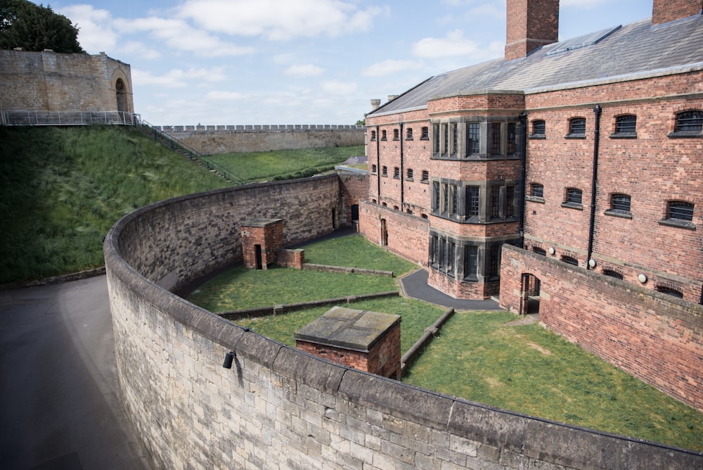 a large brick building sitting next to a lush green field