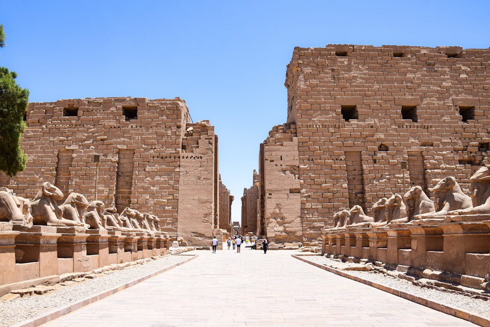 a walkway between two stone buildings with statues on each side