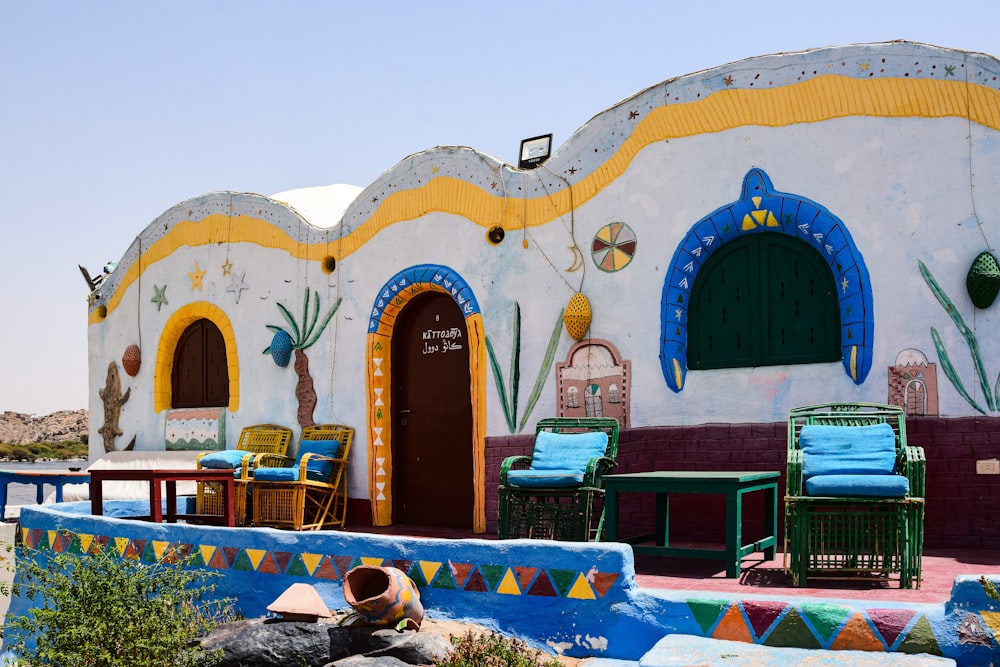 a colorfully painted building with chairs and tables in front of it