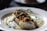 A beautifully plated dish of mussels with sauce, garnished with herbs.