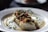 A beautifully plated dish of mussels with sauce, garnished with herbs.
