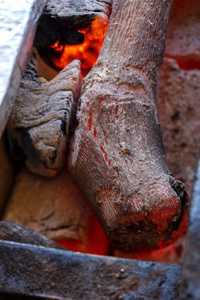 Close-up of a rustic wooden table with smoked brisket, glowing embers, and copper utensils, evoking warmth and craftsmanship.