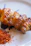 A close-up photo of a sizzling grilled chicken skewer with herbs.