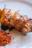 A close-up photo of a sizzling grilled chicken skewer with herbs.
