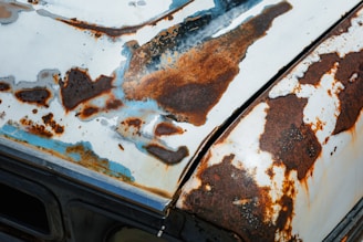 an old rusted out car with rust on the hood