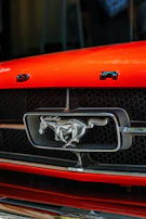 Close-up of the mach1 emblem shining on the front grille with a blurred racetrack background.
