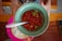 Smiling woman holding a small bowl of chipotín chili peppers in a cozy kitchen.
