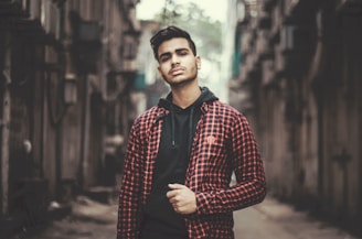 A close-up of a man wearing a bold black and red streetwear t-shirt in an urban setting.