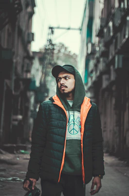 Electric orange windbreaker jacket layered over a deep navy hoodie, set against a city street backdrop.
